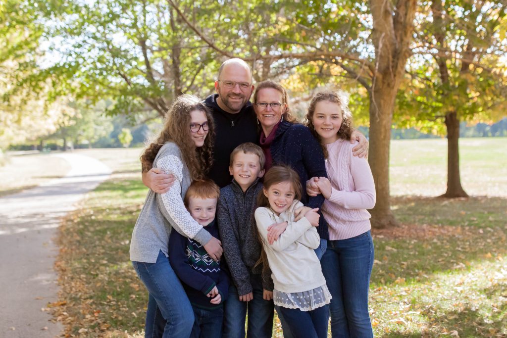 family of seven portrait outside under trees on a sunny day